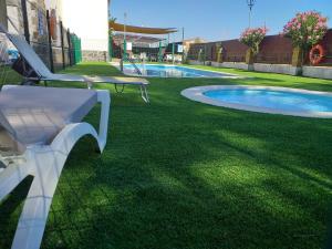 a white bench sitting on the grass next to a swimming pool at Camping las Catalinas in Ríolobos