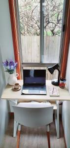uma secretária com um computador portátil em frente a uma janela em Beach Garden Getaway em Cheltenham