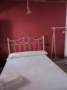 1 dormitorio con cama blanca y pared roja en SEÑORÍO DE ORGAZ III en Toledo