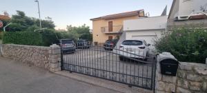 a fence with cars parked in a parking lot at Apartmani Pavlović in Krk