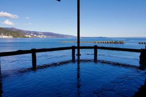Un gran cuerpo de agua con una cerca y un poste. en 熱海温泉 湯の宿 平鶴, en Atami