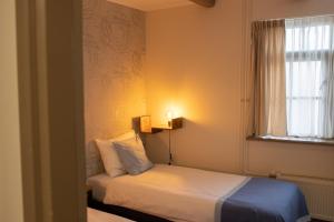 a small bedroom with a bed and a window at Hotel Almenum - het sfeervolle stadslogement - in Harlingen