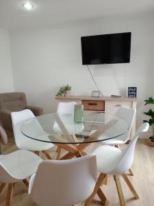 盧戈的住宿－Apartamento a Carballeira，一间设有玻璃桌和白色椅子的用餐室