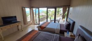a bedroom with two beds and a television and a balcony at The Kayuan in Kintamani