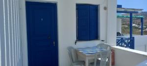 een blauwe deur en een tafel en stoelen op een huis bij Aposperitis Rooms & Apartments in Kinion