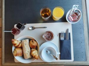 a tray with a plate of croissants and bread on it at Logis Hôtel Vannes Nord Le Clos Des Hortensias in Locqueltas