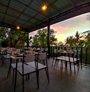 un restaurant avec des tables et des chaises et un coucher de soleil en arrière-plan. dans l'établissement Melasa House, à Senggigi