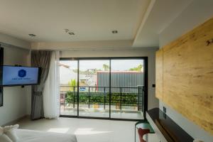 een slaapkamer met een bed en een groot raam bij Lek Lek Samui Room X Coffee Bar in Chaweng Beach