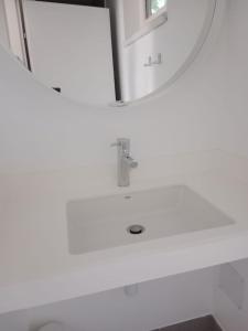 ein weißes Badezimmer mit einem Waschbecken und einem Spiegel in der Unterkunft Storchencamp Gästehaus Purbach in Purbach am Neusiedlersee