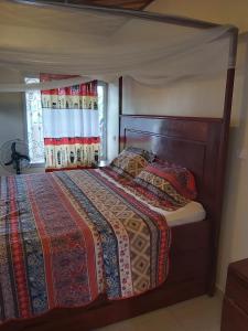 una camera con letto e testiera in legno di Deux-Palmes-Kribi, proche de la plage, confortable et adapté aux familles a Kribi