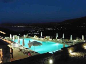 una grande piscina notturna con sedie e ombrelloni di Studio with amazing view a Exopoli