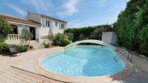 a swimming pool in a yard with a house at Maison avec piscine in Saint-Georges-dʼOrques