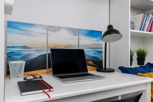 a laptop computer on a desk in front of a window at Czarnowiejska Micro Studio in Kraków