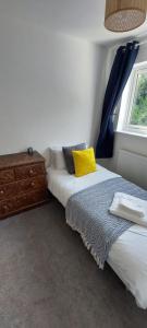 a bedroom with a bed with a yellow pillow and a dresser at Modern Town House in Mid Wales in Knighton