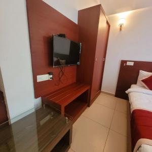 una habitación de hotel con TV en la pared en Four Squares Inn, Technopark phase 3, en Trivandrum