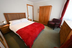 una camera da letto con un grande letto con una coperta rossa di Swallow Cottage a Fort William