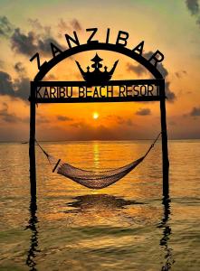 - un hamac dans l'océan avec un coucher de soleil en arrière-plan dans l'établissement Karibu Beach Resort, à Pongwe