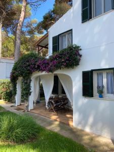 a white house with a patio with purple flowers at Bellver 1, Ciutadella-Cala Blanca in Cala Blanca