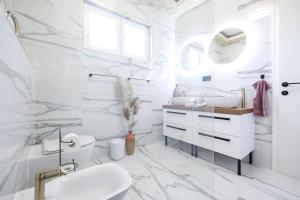 een witte badkamer met een wastafel en een spiegel bij Oscar & Leo Apartments in Zadar