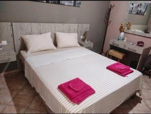 a bedroom with a large bed with pink towels on it at Cretan Utopia Maisonette in Kavrokhórion