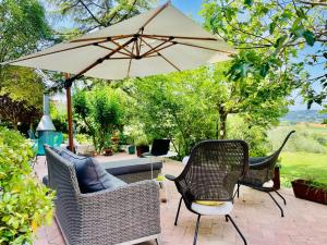 un patio con 2 sillas y una sombrilla en Agriturismo CasaViVa, en Pozzo