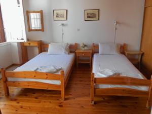 two beds in a room with wooden floors at Aggela Guesthouse in Skopelos Town