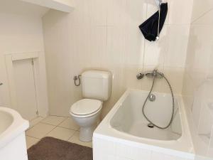 a white bathroom with a toilet and a bath tub at Sweet home in Brussels
