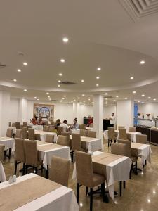 un restaurante con mesas y sillas blancas y gente en Hotel Felizya Kemer, en Kemer