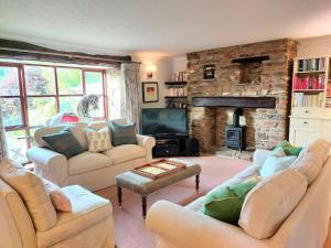 a living room with couches and a stone fireplace at Brook Barn in Malborough