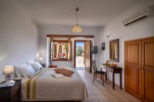 a bedroom with a bed and a desk and a table at Alkifron Hotel in Kala Nera