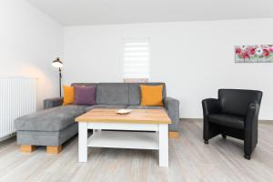 ein Wohnzimmer mit einem Sofa, einem Tisch und einem Stuhl in der Unterkunft Ferienwohnungen Huus up Siel in Esens