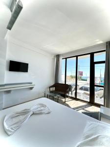 a white bedroom with a bed and a balcony at Seaside Inn & Suites in Costinesti