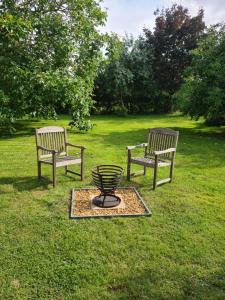 two benches sitting in the grass in a park at The Potting Shed in Manuden