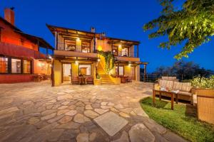 a large house with a stone patio at night at Alkifron Hotel in Kala Nera