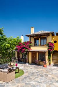 a house with pink flowers and a patio at Alkifron Hotel in Kala Nera