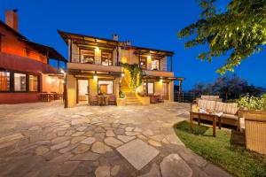 a large house with a stone patio at night at Alkifron Hotel in Kala Nera