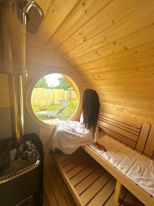 a woman sitting in a sauna looking out the window at Penzion Arendel in Líšnice