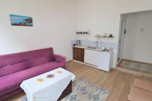 a living room with a purple couch and a kitchen at Aymena B in Kuşadası