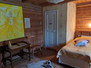 a bedroom with a bed and a desk with a painting on the wall at Nukula Guestrooms in Oravasaari