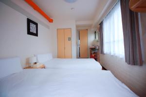 a bedroom with two white beds and a window at HOTEL AARON通天東 in Osaka