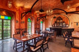 un restaurant avec des tables et des chaises en bois ainsi qu'un bar dans l'établissement Silva Heritage Resort Goa, à Benaulim