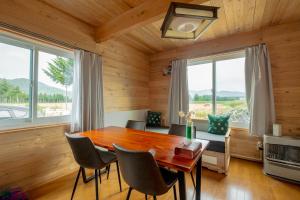 comedor con mesa de madera y sillas en Furano Log House Farm Resort, en Furano