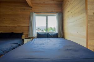 um quarto com uma cama e uma janela em Furano Log House Farm Resort em Furano