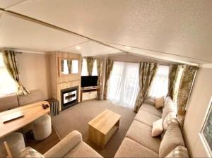 a living room with a couch and a table and a tv at Private Lakeside Cabin in St Austell