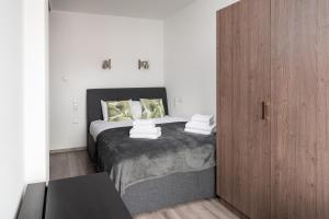 een slaapkamer met een bed en een houten kast bij Wola Modern Apartment in Warschau