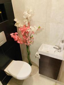 a bathroom with a toilet and a sink and flowers at Apartamenty Every Sky Plac Ratuszowy 30 in Jelenia Góra