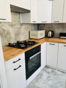 a kitchen with white cabinets and a stove top oven at Apartamenty Every Sky Plac Ratuszowy 30 in Jelenia Góra
