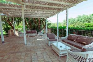 patio z kanapą i krzesłami pod pergolą w obiekcie Casale del Murgese Country Resort w mieście Savelletri di Fasano