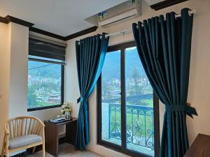 SAPA COSY HOTEL في سابا: غرفة بها نافذة مع ستائر زرقاء وكرسي