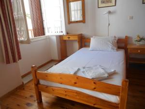 Schlafzimmer mit einem Holzbett mit weißer Bettwäsche in der Unterkunft Aggela Guesthouse in Skopelos